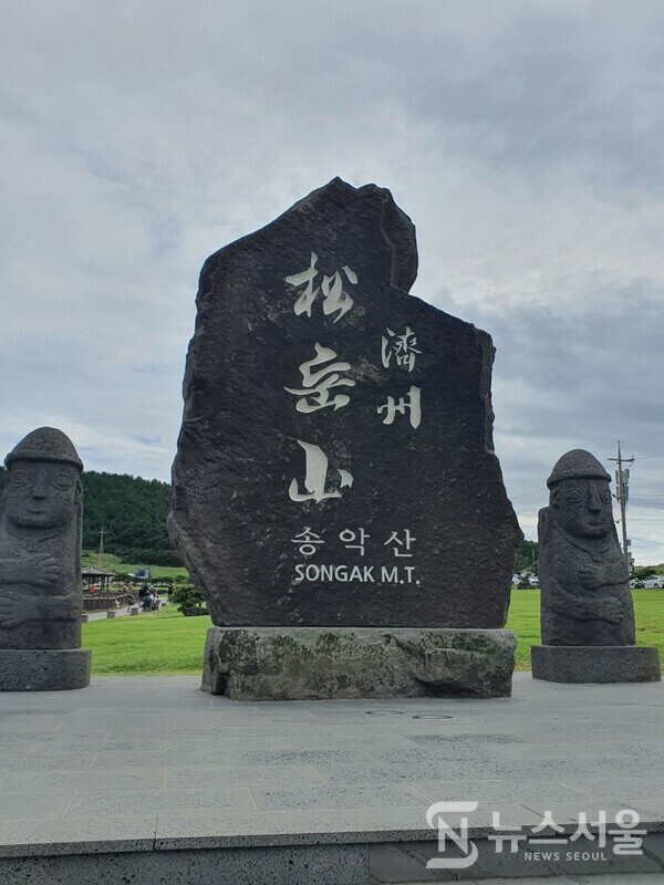 송악산 입구 표지석. 제주도 서귀포시 대정읍 상모리에 있는 송악산 주차장 인근 송악산을 오르는 입구에 검은 현무암으로 된 제주 송악산 표지석이 있으며, 표지석 양 옆으로 돌하르방이 보초를 서고 있다.